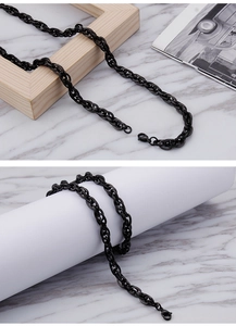 Close-up of black stainless steel square link chain necklace on marble background