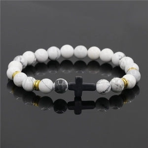 Dettaglio del bracciale con perline in turchese bianco, croce nera e accenti dorati