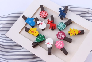 Close-up of assorted Christmas wooden clips with Merry Xmas text on striped background