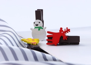 Detail of Christmas wooden clips featuring snowman, reindeer, and tree designs on white surface