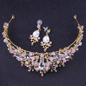 Detailed top view of golden bridal crown and earrings set with pink crystals on black base