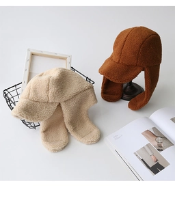 Dettaglio del cappello con paraorecchie in lana d'agnello in beige e marrone caramello