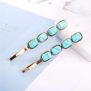 Detail shot of golden barrette hair clips with emerald green turquoise square stones