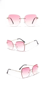 Close-up of frameless sunglasses with pink gradient lenses and gold metal temples