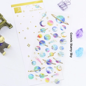 Close-up of starry universe theme stickers with gold foil details on marble surface