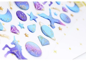 Macro shot of 3D galaxy stickers featuring blue planets and gold foil constellations