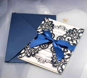 Detail of navy laser-cut invitation with a satin bow on a soft tulle background