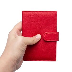 Handheld red PU leather passport holder with buckle closure and pebbled texture