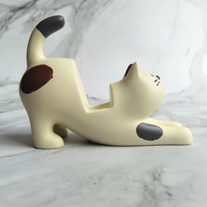 Macro side view of a minimalist cream resin cat phone stand with matte finish and spots
