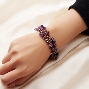 Detail of bohemian purple crystal cluster bracelet with gold chain on silk background