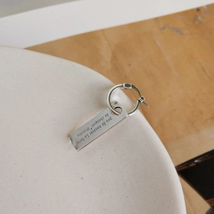 Macro detail of 925 sterling silver rectangular earrings with engraved French quote