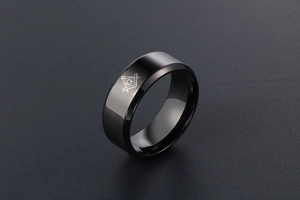 Nahaufnahme eines polierten schwarzen Titanrings mit graviertem Freimaurersymbol und G-Zeichen