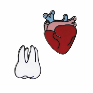 Detail of red anatomical heart and white tooth enamel pins set on white background