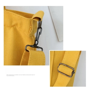 Detailed close-up of metal hooks and adjustable strap hardware on yellow canvas bag