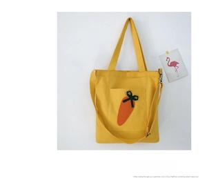 Detail of yellow canvas tote bag with carrot embroidery and adjustable strap