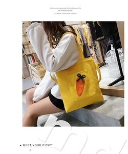 Detail view of yellow canvas tote bag featuring cute 3D carrot pocket and shoulder strap