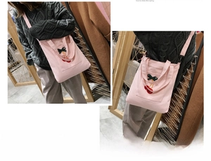 Detail of pink canvas tote bag featuring cherry embroidery and green bow decoration