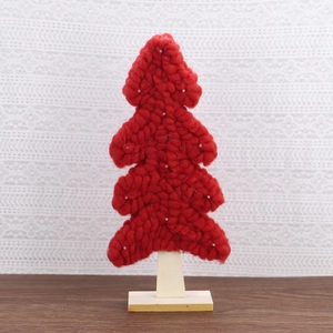 Macro shot of red chunky knit Christmas tree decoration with beads on a wooden base