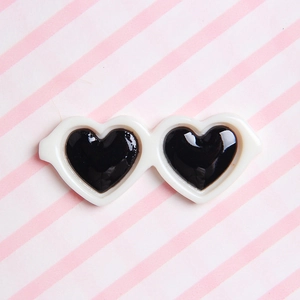Top-down view of a cute heart-shaped pet sunglass with white frame and black lenses