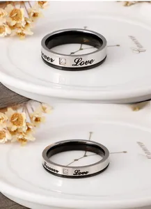 Gros plan de bagues de couple argent et noir gravées Forever Love avec un zircon serti