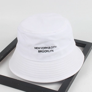 White cotton bucket hat with black New York City embroidery on a minimalist wood frame