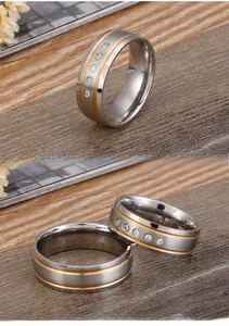 Detail of brushed stainless steel couple rings with gold inlay lines and inlaid zircons