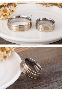 Detail of frosted stainless steel couple rings with gold edges and inlaid zircons