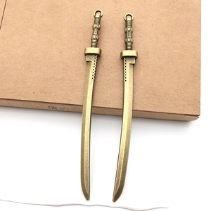 Dettaglio di due ciondoli a forma di spada in bronzo per gioielli DIY e cosplay