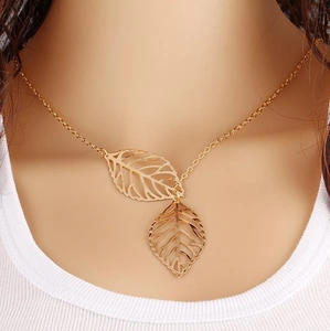 Close-up of golden double leaf pendant necklace with intricate hollowed-out design details