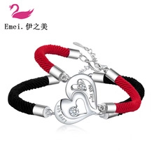 Close-up of heart-shaped magnetic pendants on red and black braided couple bracelets
