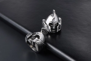 Detail of vintage silver Spartan helmet skull rings on a black leather texture background