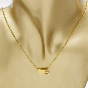 Golden stainless steel heart pendant necklace with letter S charm on gold mannequin