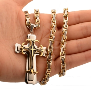Close-up of a two-tone cross pendant necklace with Byzantine chain in gold and silver