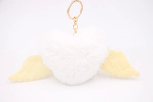 Detailed close-up of a white plush heart keychain with yellow wings and gold metal ring