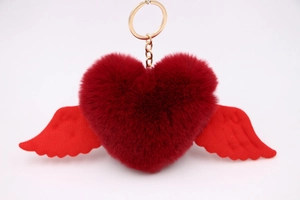 Detail of plush heart keychain with red wings and a golden metal ring attachment