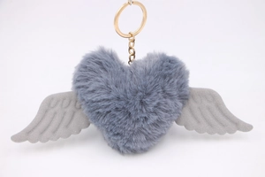 Macro detail of plush heart keychain with embossed wings and gold metal ring