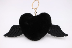Close-up of black fluffy heart pendant with wings and golden metal keychain