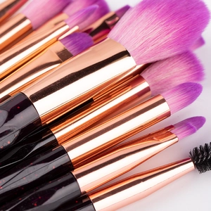 Detail of glittery black handles and rose gold ferrules on purple makeup brushes