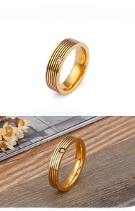 Macro detail of gold stainless steel ring with parallel grooves and centered zircon stone