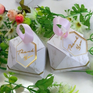 Detail of marble pattern diamond favor box with pink ribbon and gold foil thank you tag