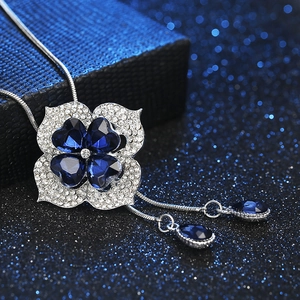 Macro detail of silver four-leaf clover necklace with dark blue gems and rhinestones