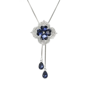 Blue crystal clover pendant necklace with silver chain and teardrop accents on white background