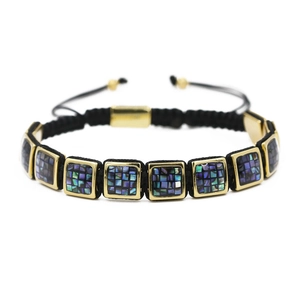 Detail of square gold link bracelet with mosaic shell inlays and black cord