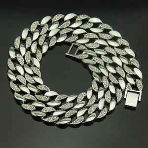 Hip hop silver Cuban link chain with rhinestones for men, coiled on black background