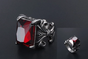 Macro detail of punk style steel ring with red rectangular stone and floral engraving