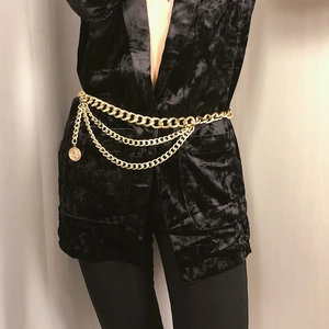 Close-up of gold layered chain belt with vintage coin pendant on black velvet top