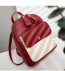 Detail of burgundy and beige leather backpack featuring a gold snap button front pocket