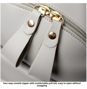 Close-up of smooth dual metal zippers with leather pulls on a grey minimalist bag