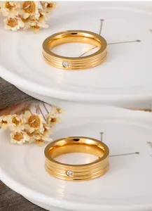 Detail of gold ring with three parallel grooves and a sparkling centered zircon stone