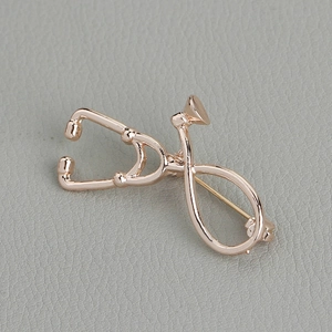 Close-up of a polished rose gold stethoscope brooch with a detailed medical design